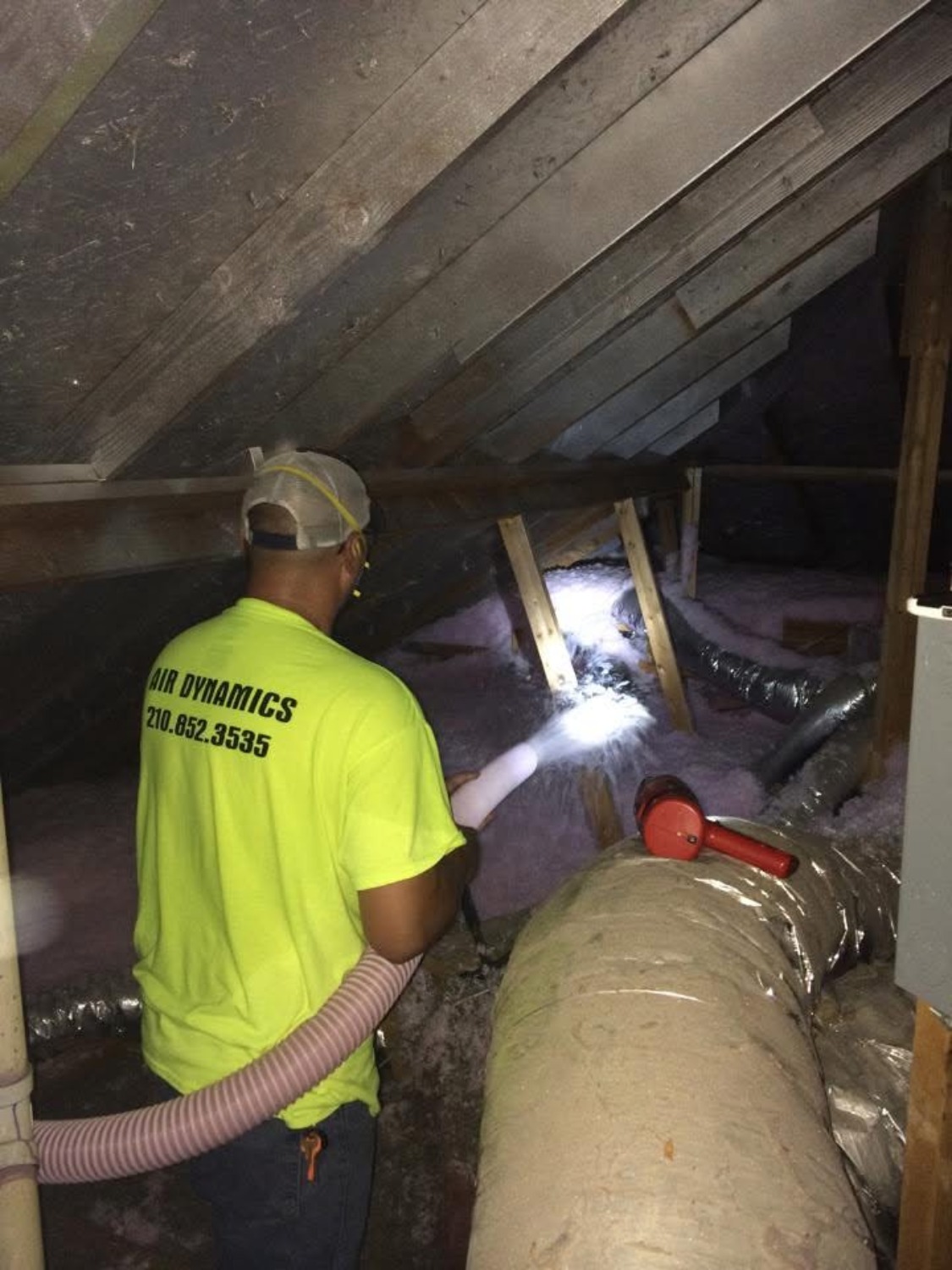 An Air Dynamics technician working in an attic