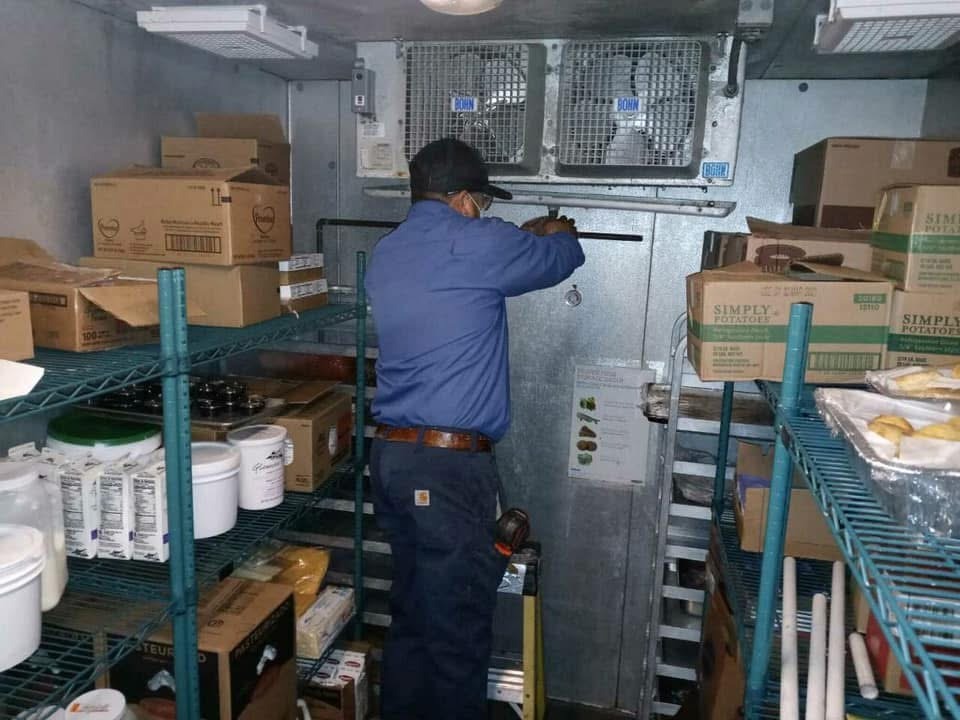 An Air Dynamics technician servicing a commercial walk-in cooler